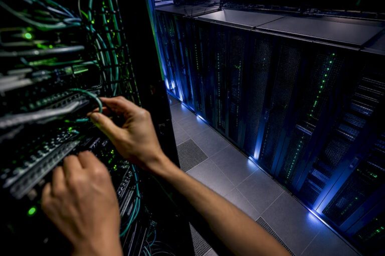 Mains ajustant les câbles d'un serveur dans une installation technique