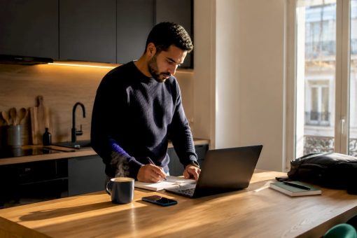 Dirigeant de petite entreprise concentré sur son travail dans un bureau baigné de lumière naturelle.