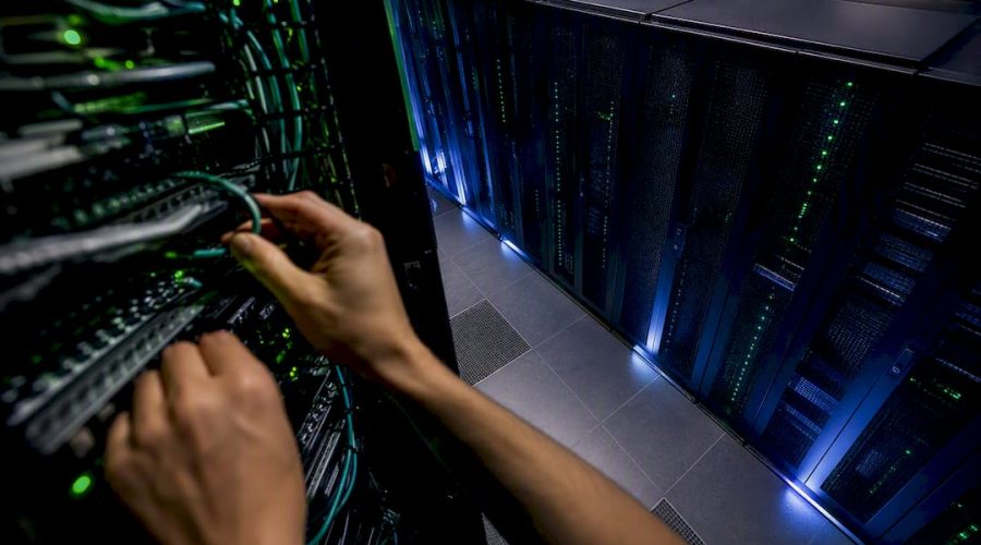 Mains ajustant les câbles d'un serveur dans une installation technique
